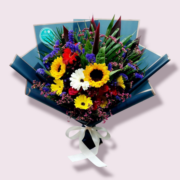 A bigger bouquet, featuring a mix of yellow and red flowers and green foliage, wrapped in paper with a ribbon.