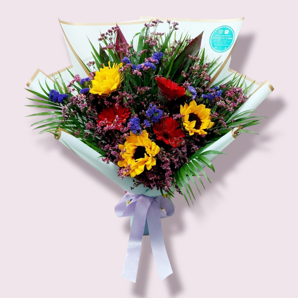 A big bouquet, featuring a mix of yellow and red flowers and green foliage, wrapped in paper with a ribbon.